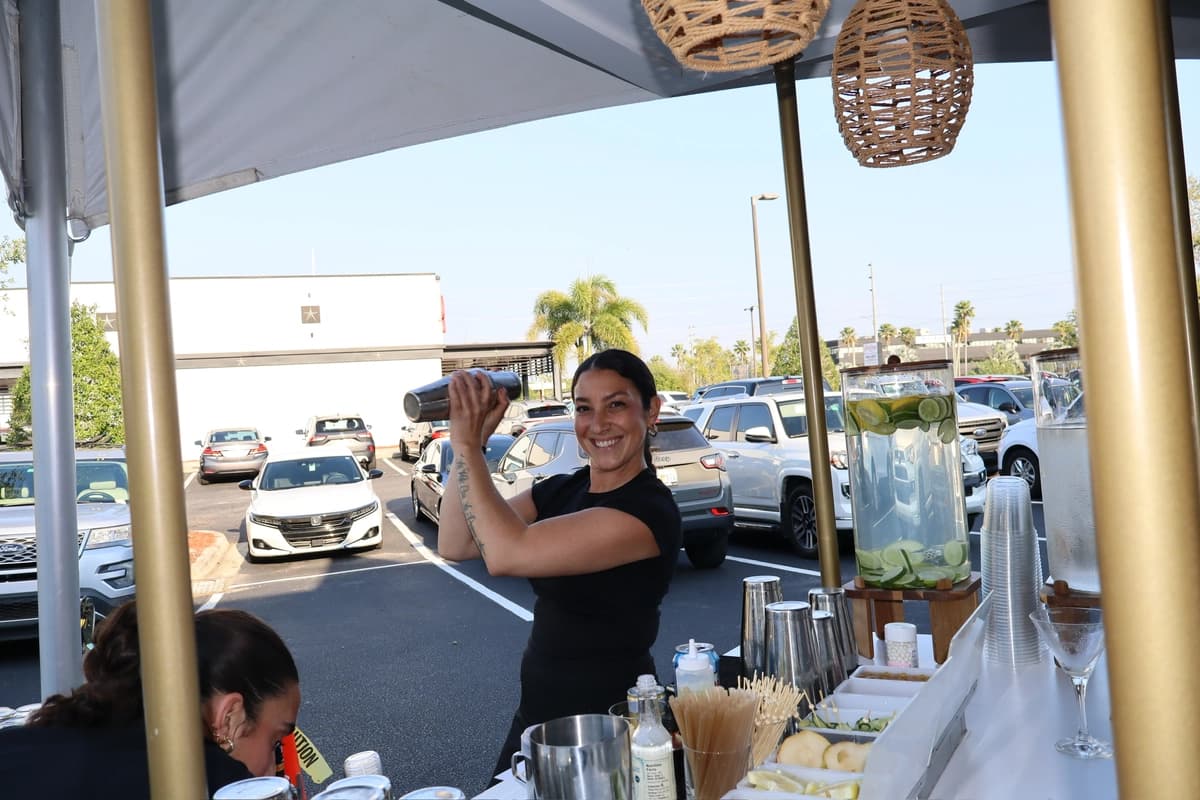 TB Mixology bartender shaking cocktail under outdoor canopy with pendant lights