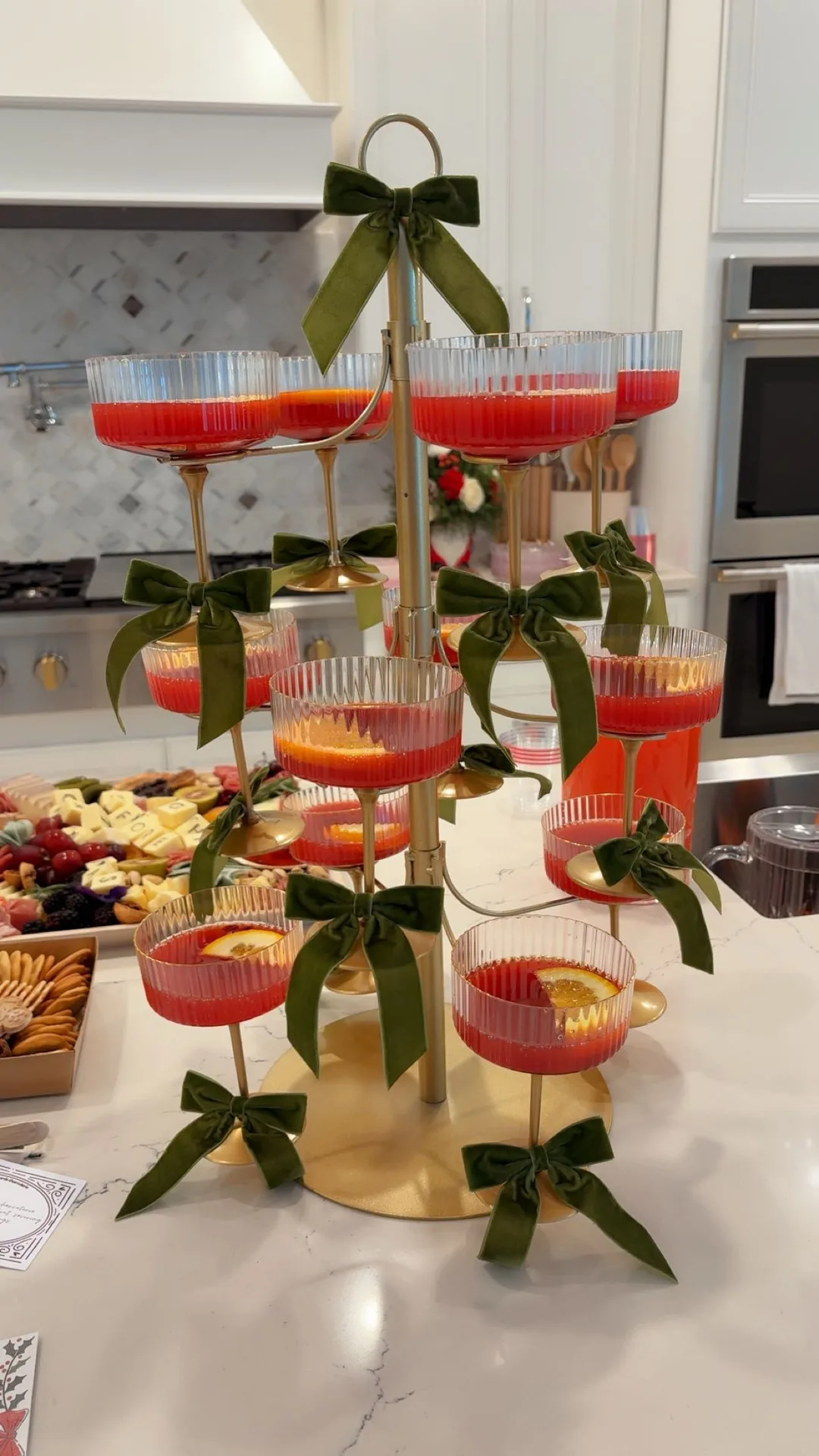 Holiday batch cocktails displayed on a tower of coupe glasses with green bows