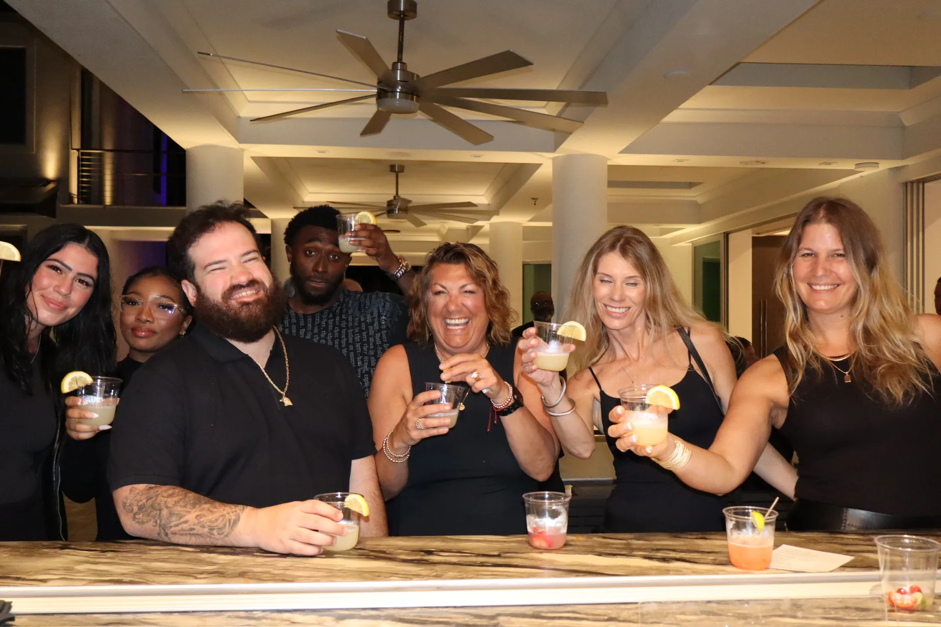 Group raising cocktails and shots for cheers behind bar at birthday party