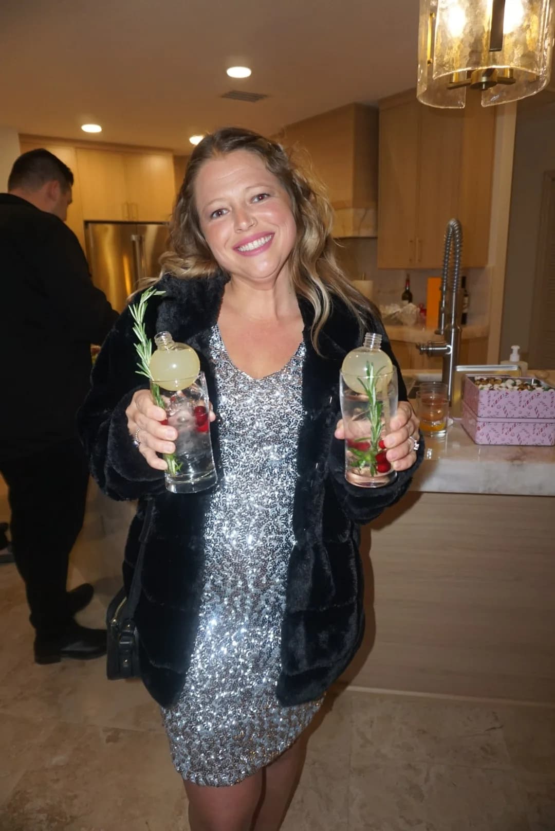 Bartender holding two rosemary garnished cocktails at Christmas party