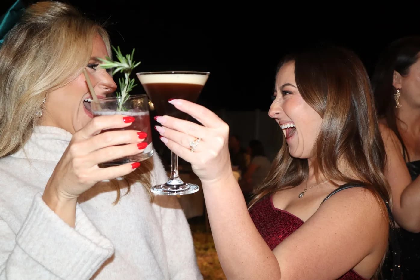 Friends laughing and cheersing cocktails at Christmas party