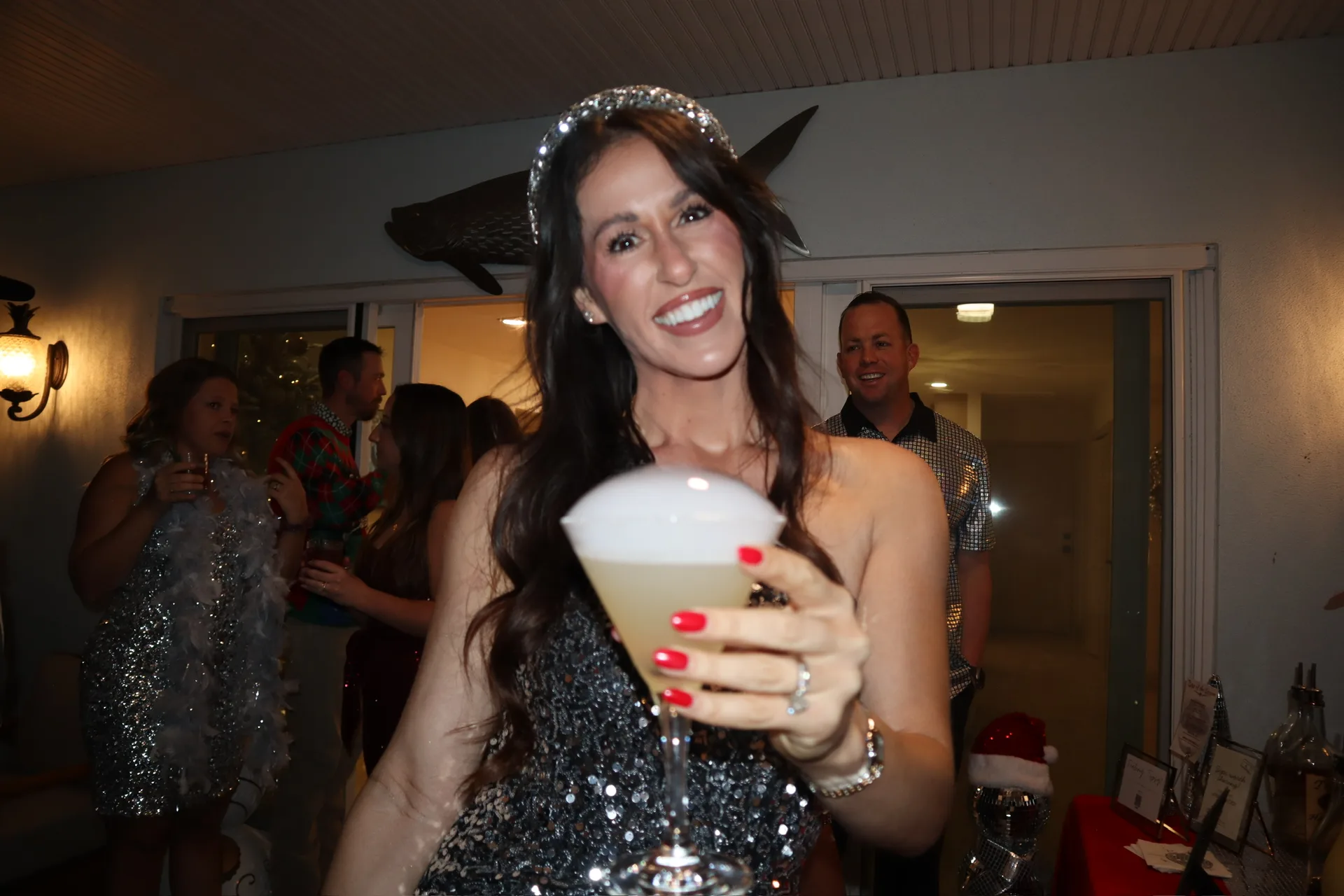 Guest in sparkle headband holding lemon drop martini at Christmas party
