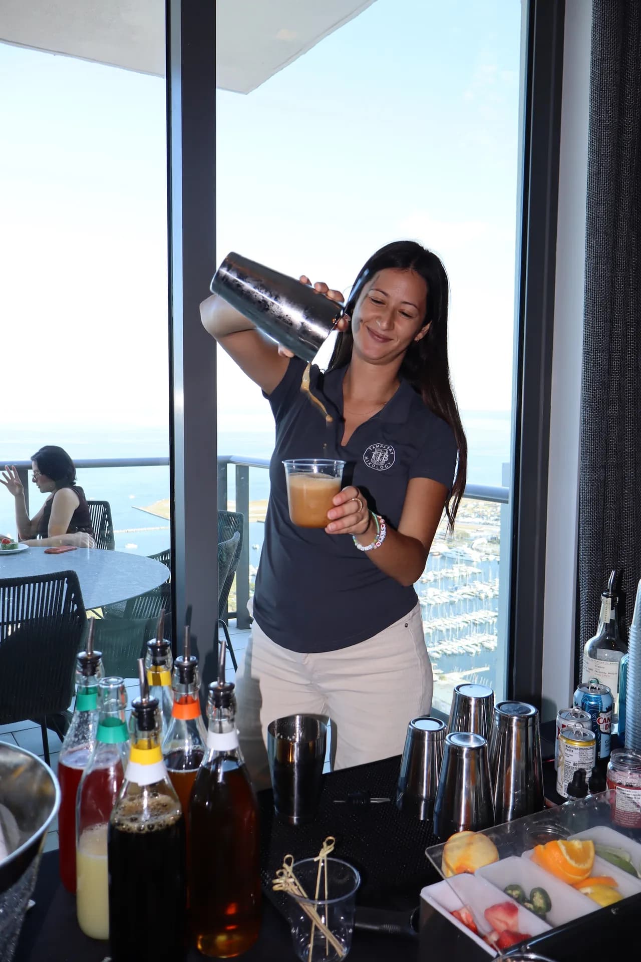 Bartender pouring cocktail with marina and skyline view