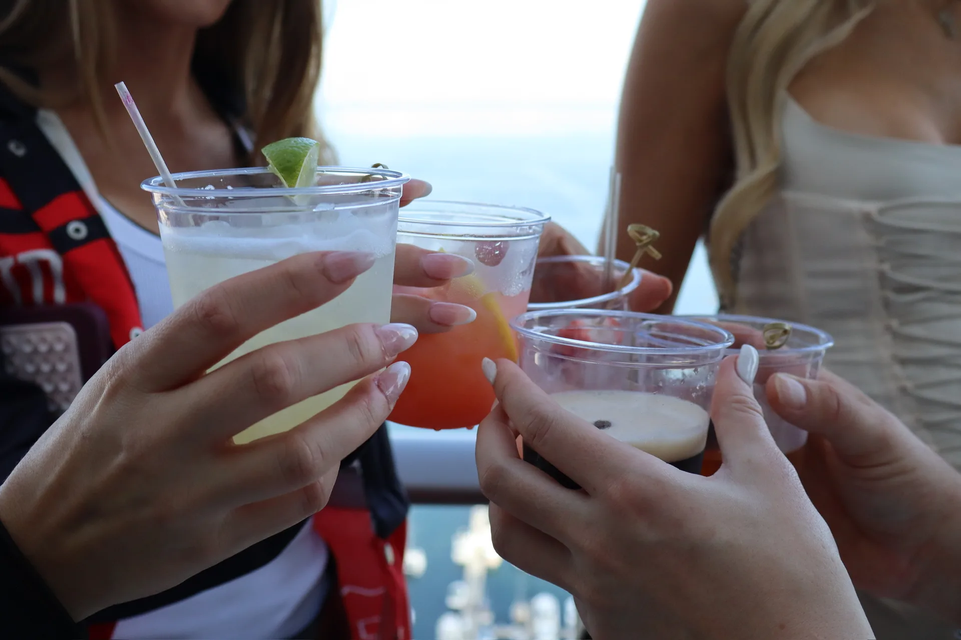 Closeup of friends cheersing cocktails with ocean view