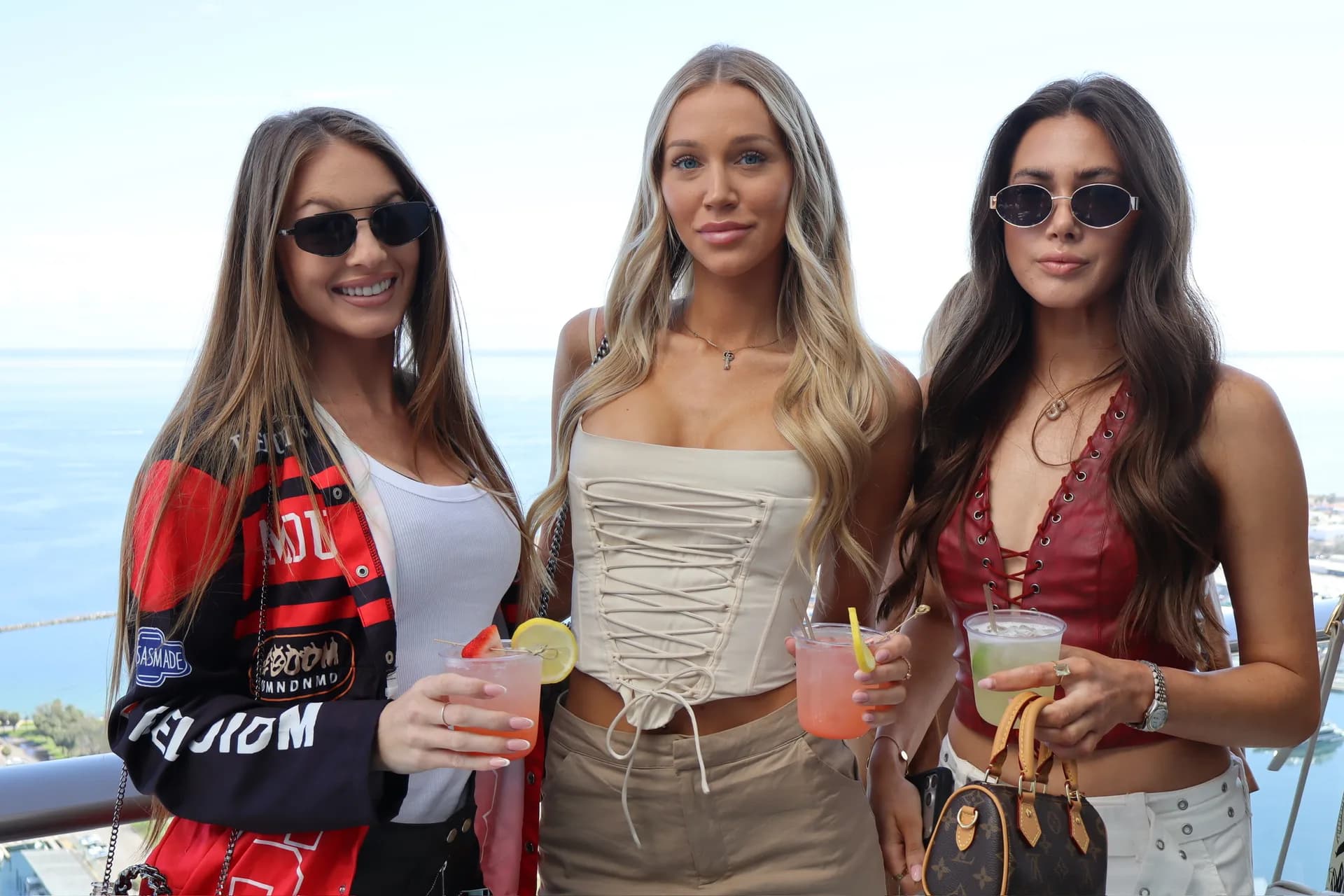 Three friends holding cocktails on ocean view balcony