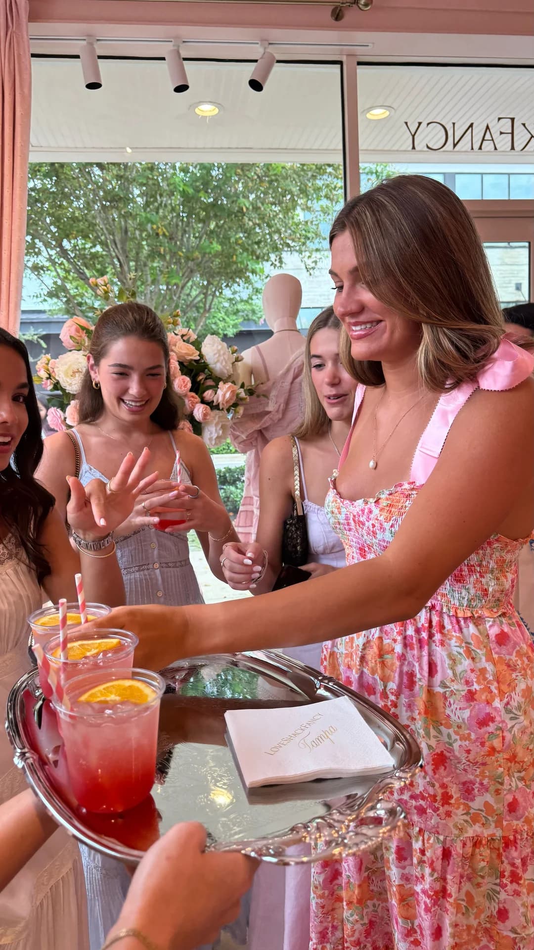 Guests taking cocktails from a silver tray inside the LoveShackFancy boutique