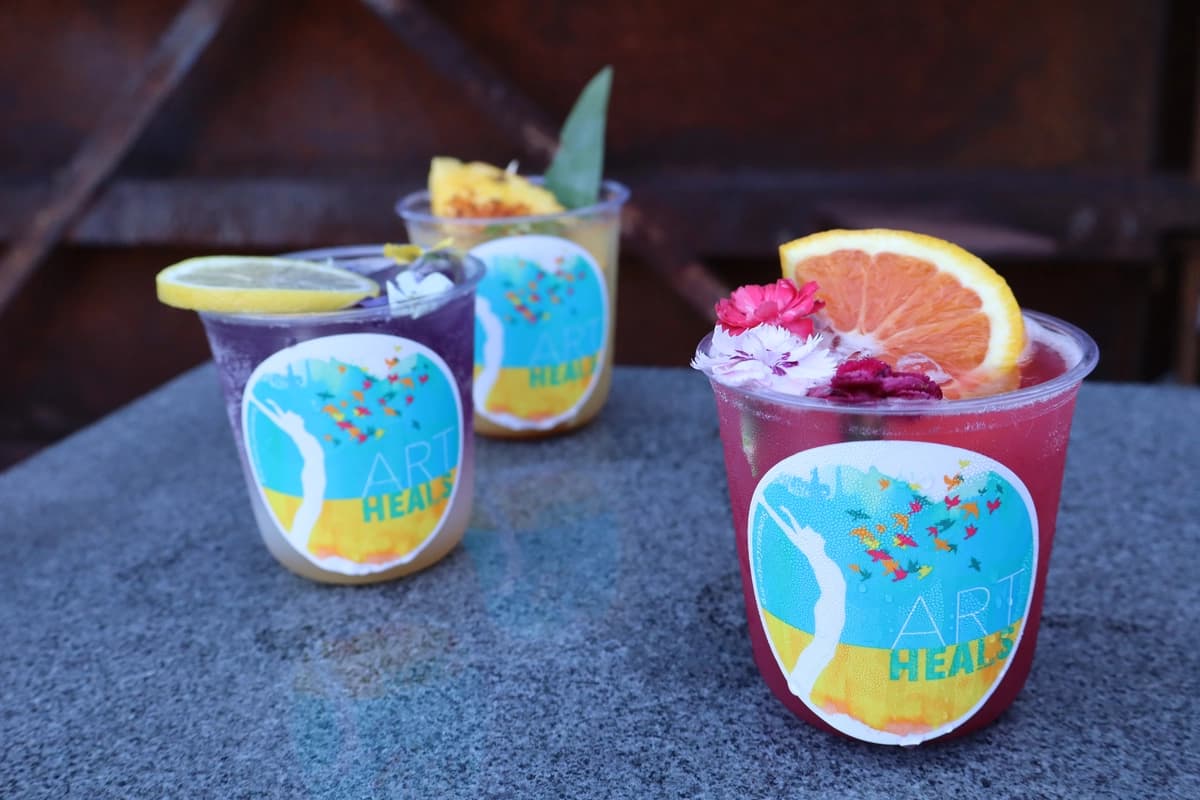 Three Art Heals mocktails with garnishes on rustic industrial backdrop