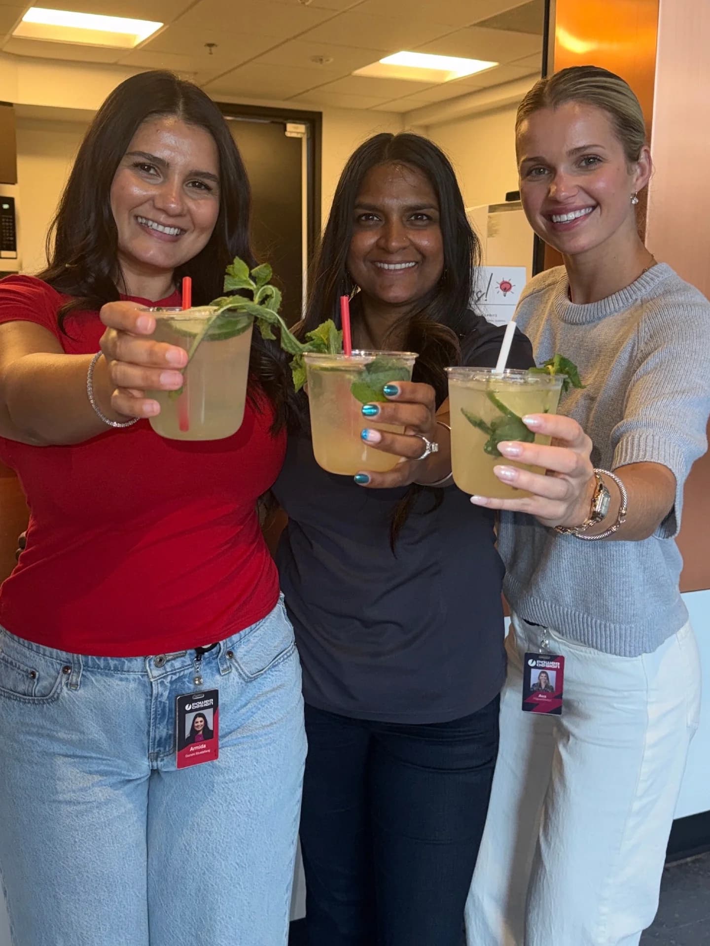 Three employees toasting mint-garnished mocktails at a corporate event