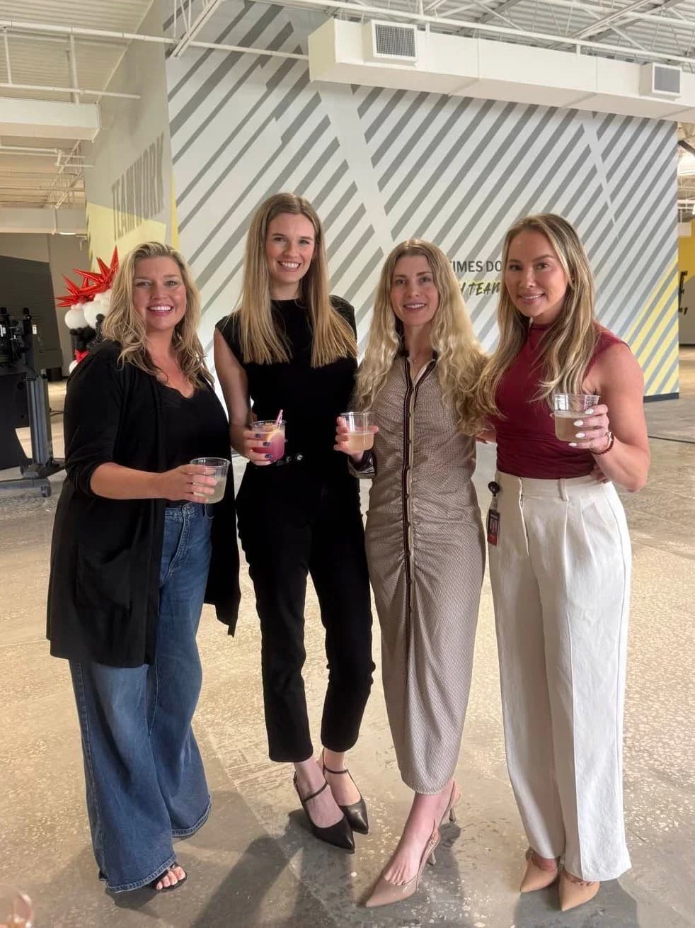 Four team members posing with cocktails at a Power Design company event