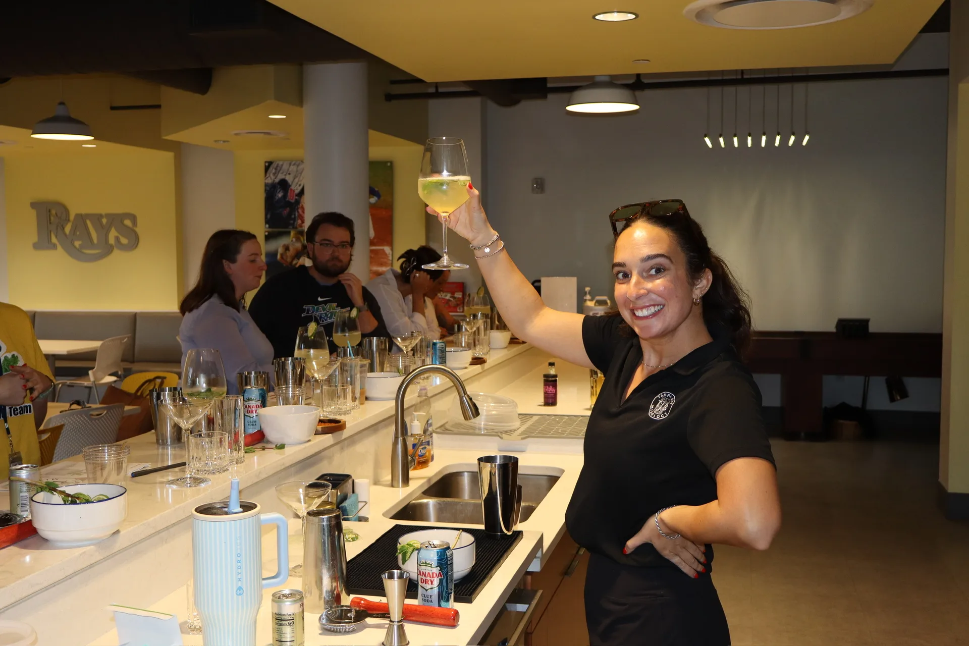 TB Mixology instructor raising glass with Rays logo in background