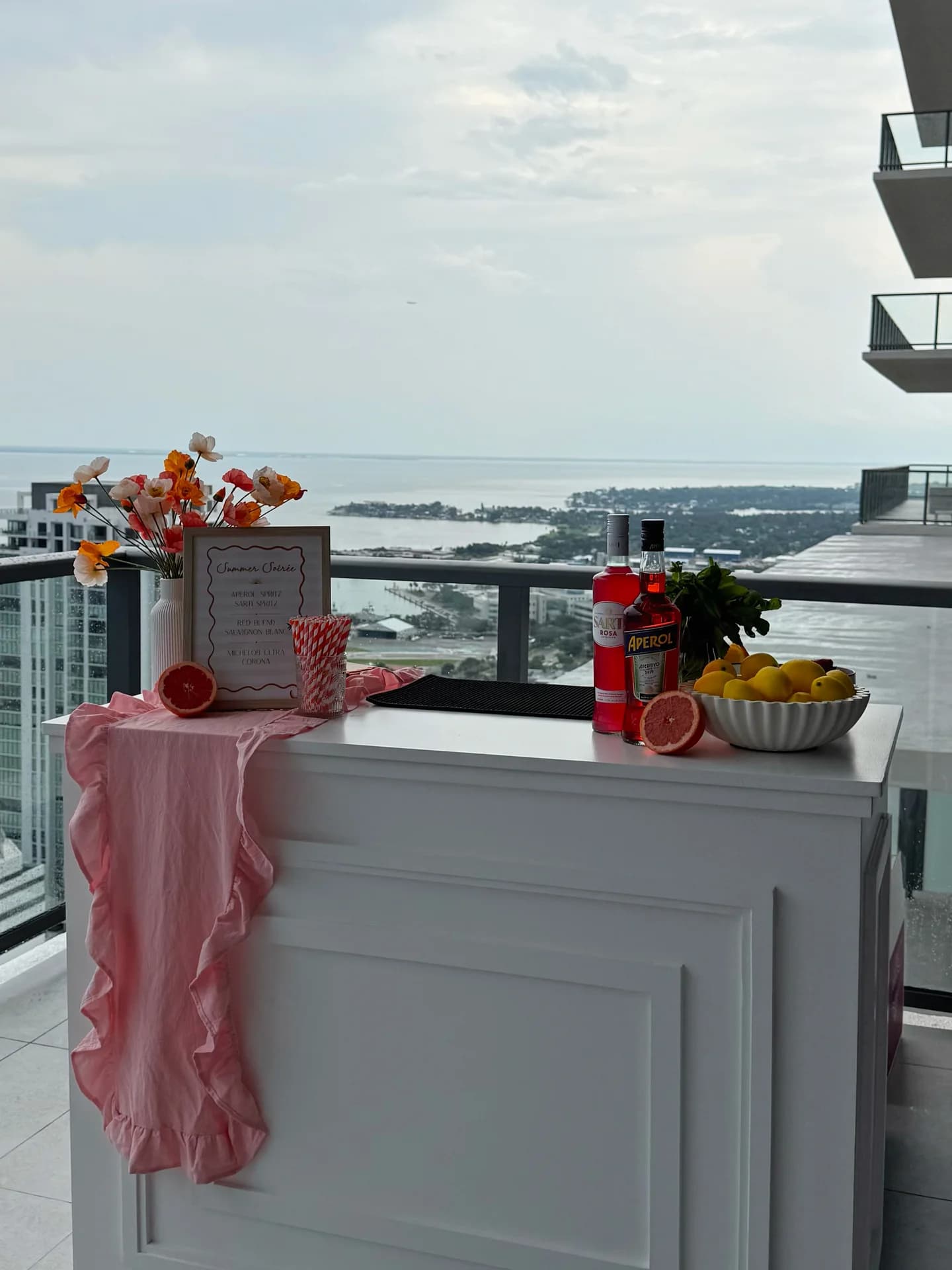 White mobile bar on a highrise balcony with poppies and a waterfront view
