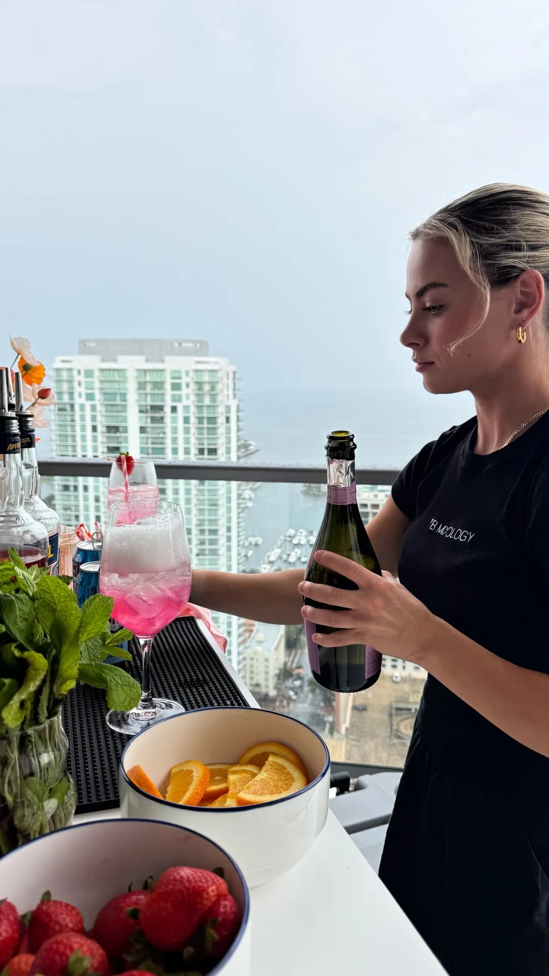 TB Mixology bartender pouring prosecco into a spritz above the Tampa skyline