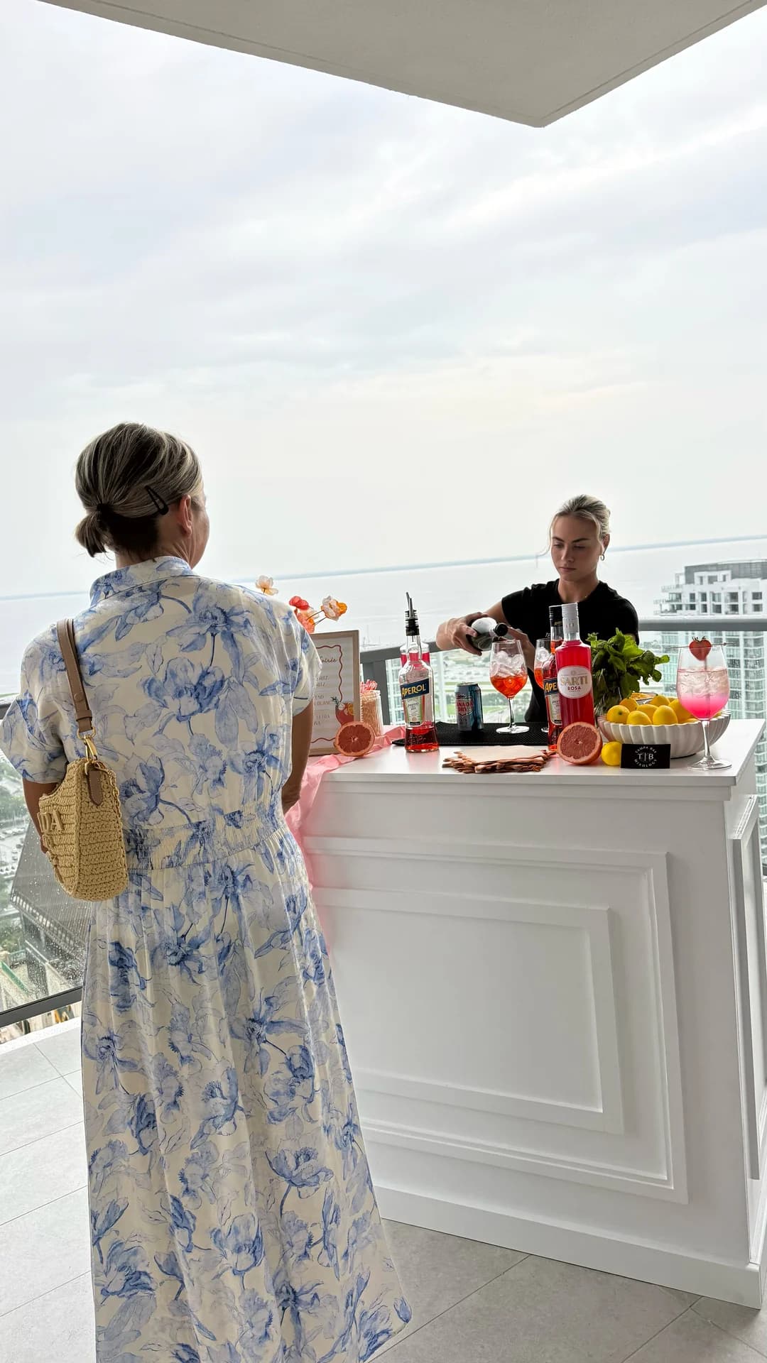 Guest in a blue floral dress ordering at the white mobile bar