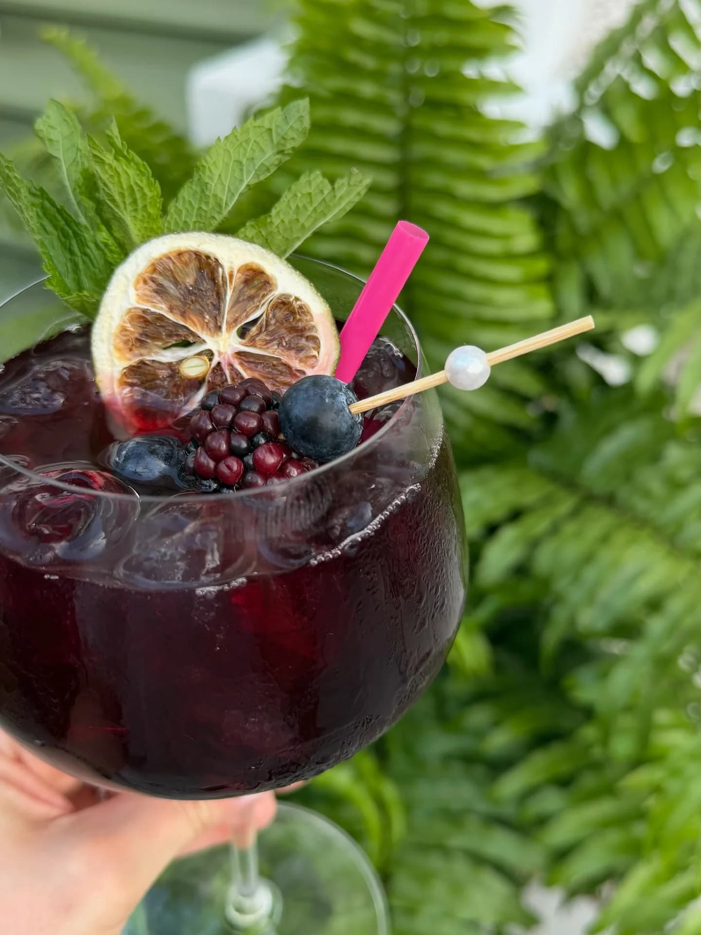 Deep blackberry cocktail with dried citrus wheel and fresh mint