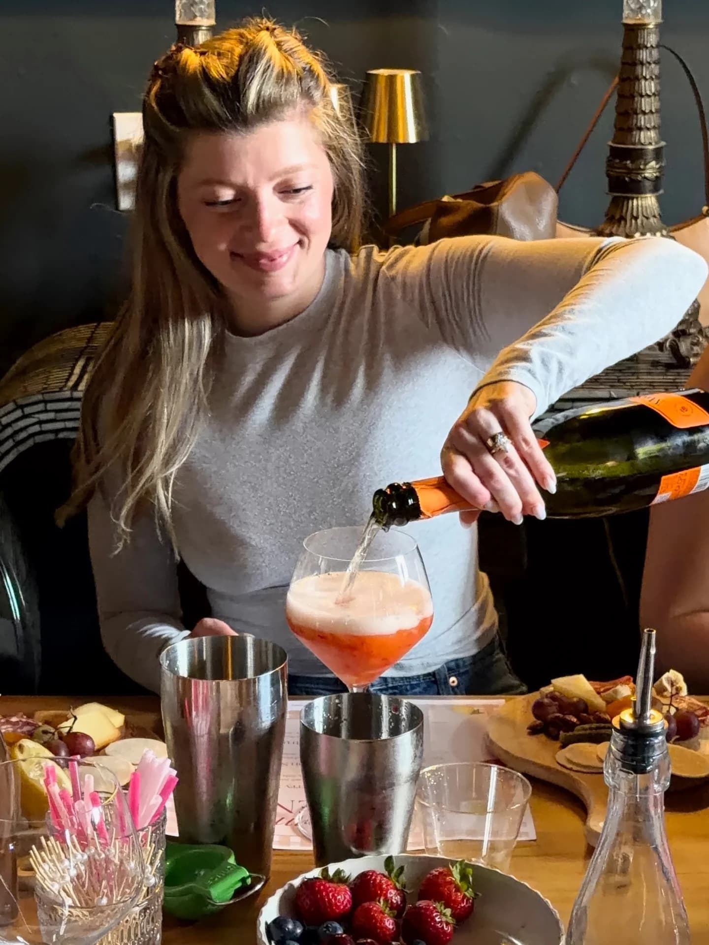 Host pouring prosecco into a coupe during a hosted cocktail class