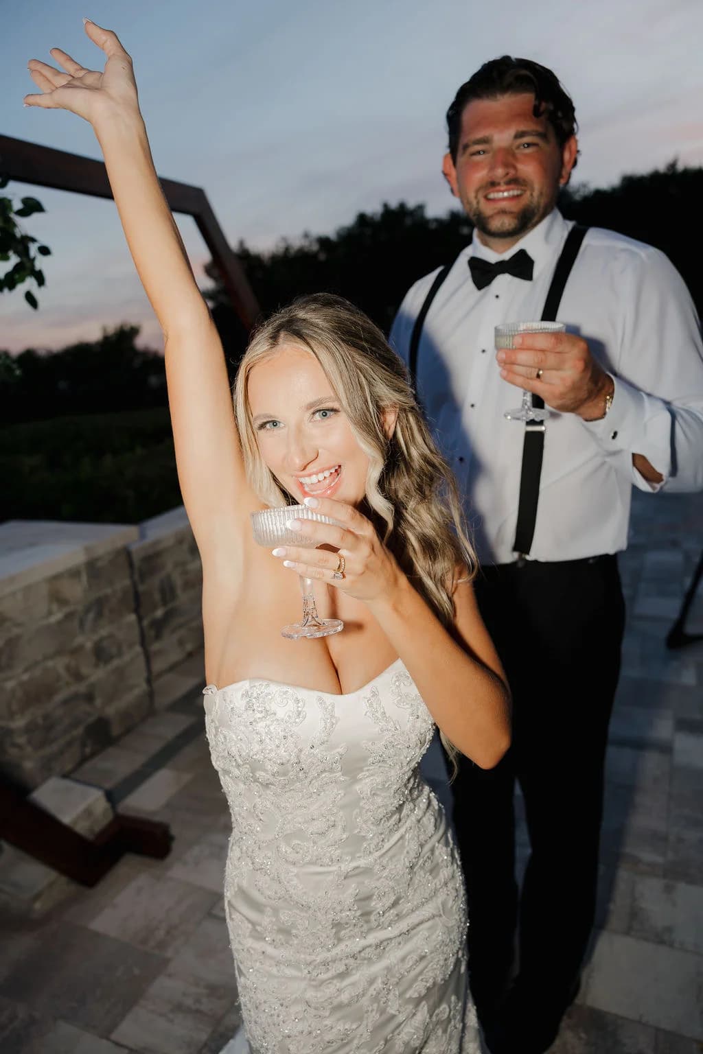 Bride and groom celebrating with champagne coupes at dusk
