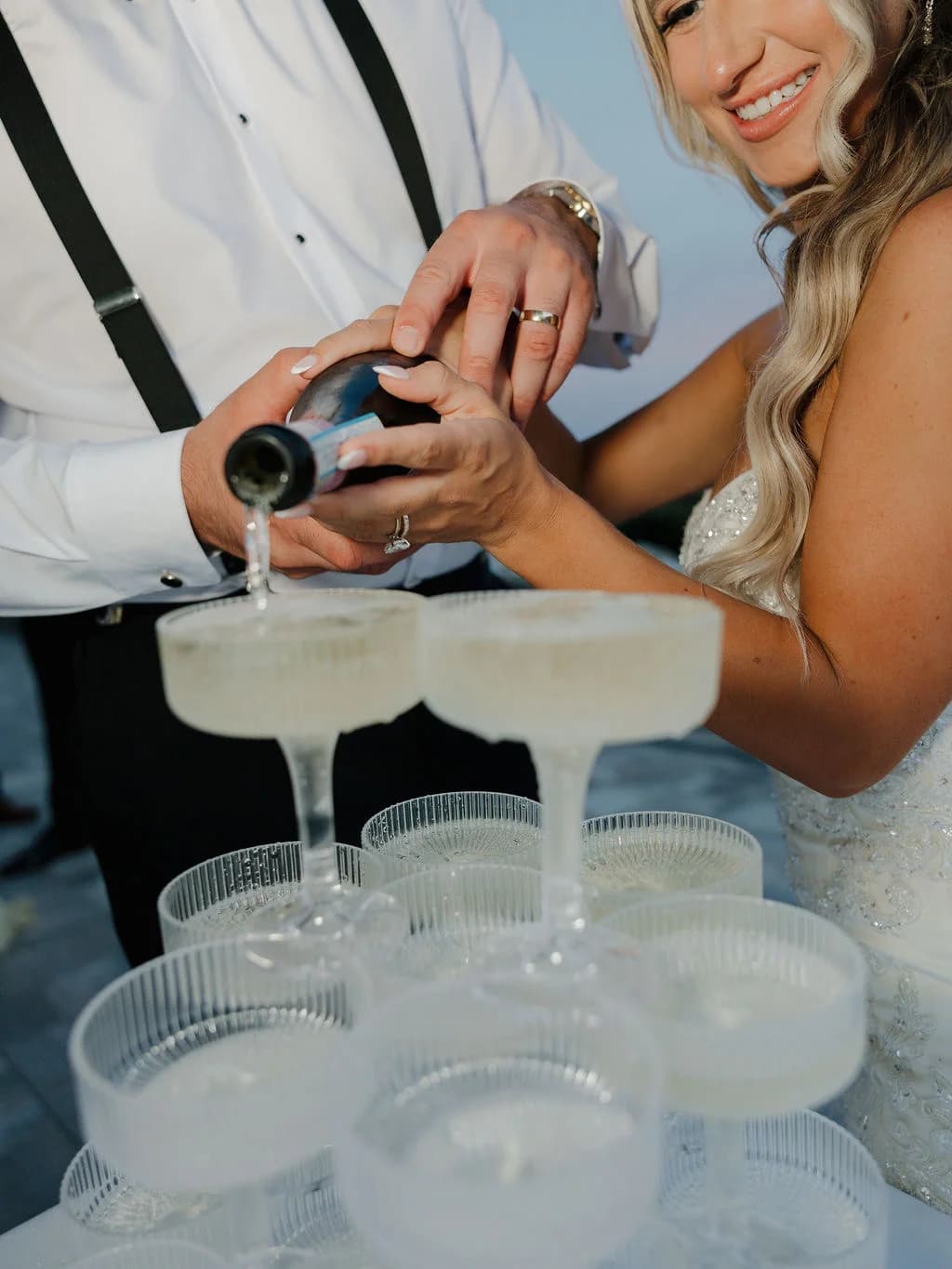 Close-up of champagne being poured into the top coupe of a wedding champagne tower
