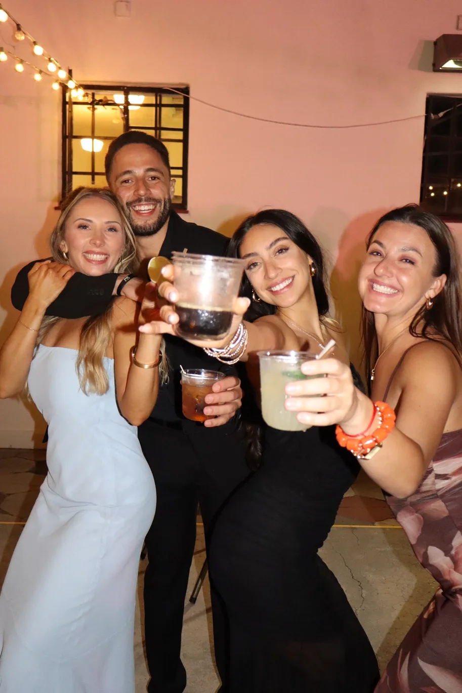 Girlfriends cheersing cocktails at an evening wedding patio party